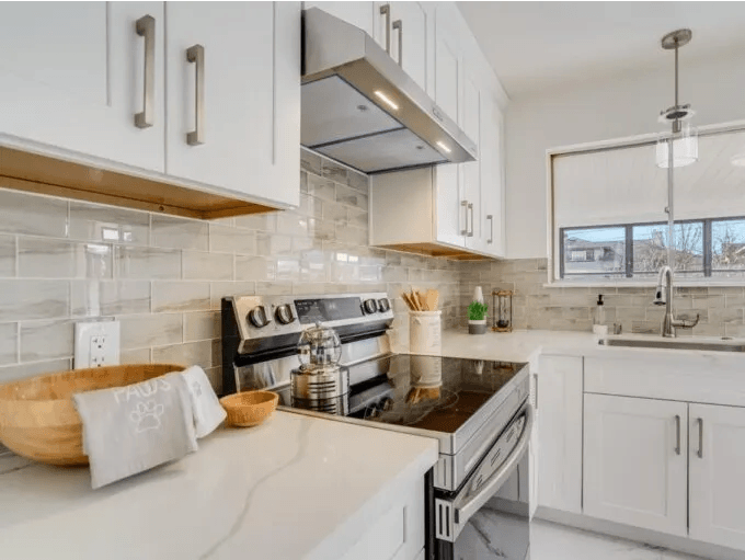 A kitchen with white cabinets , a stove and a sink.
