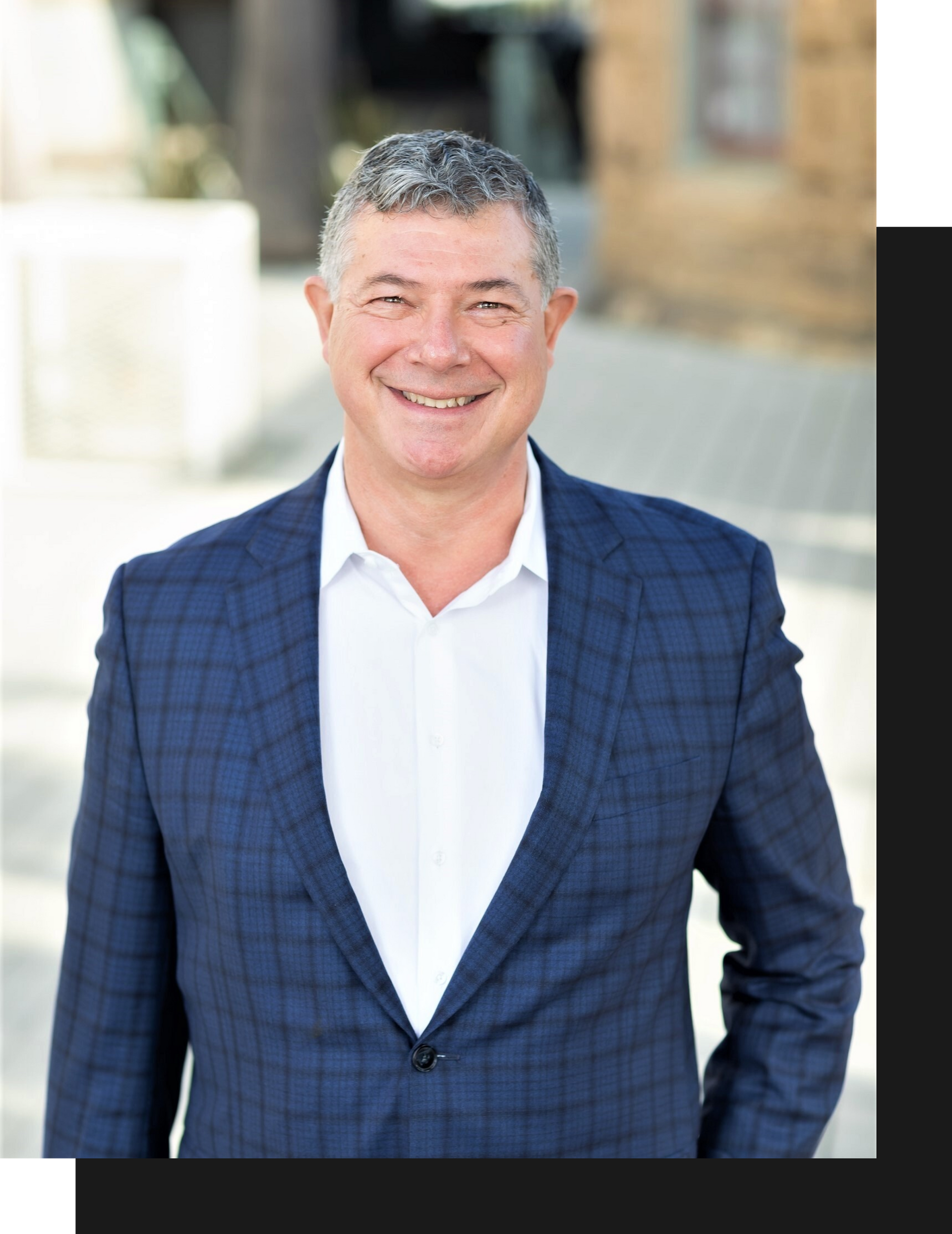 A man in a suit and white shirt is smiling for the camera