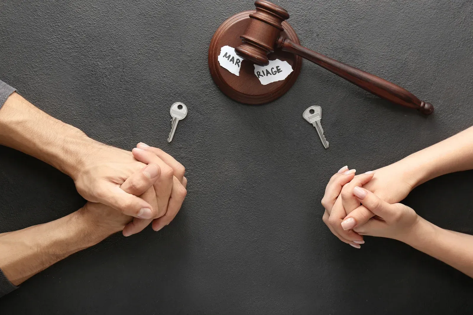 Hands and keys separated by a gavel and torn paper with