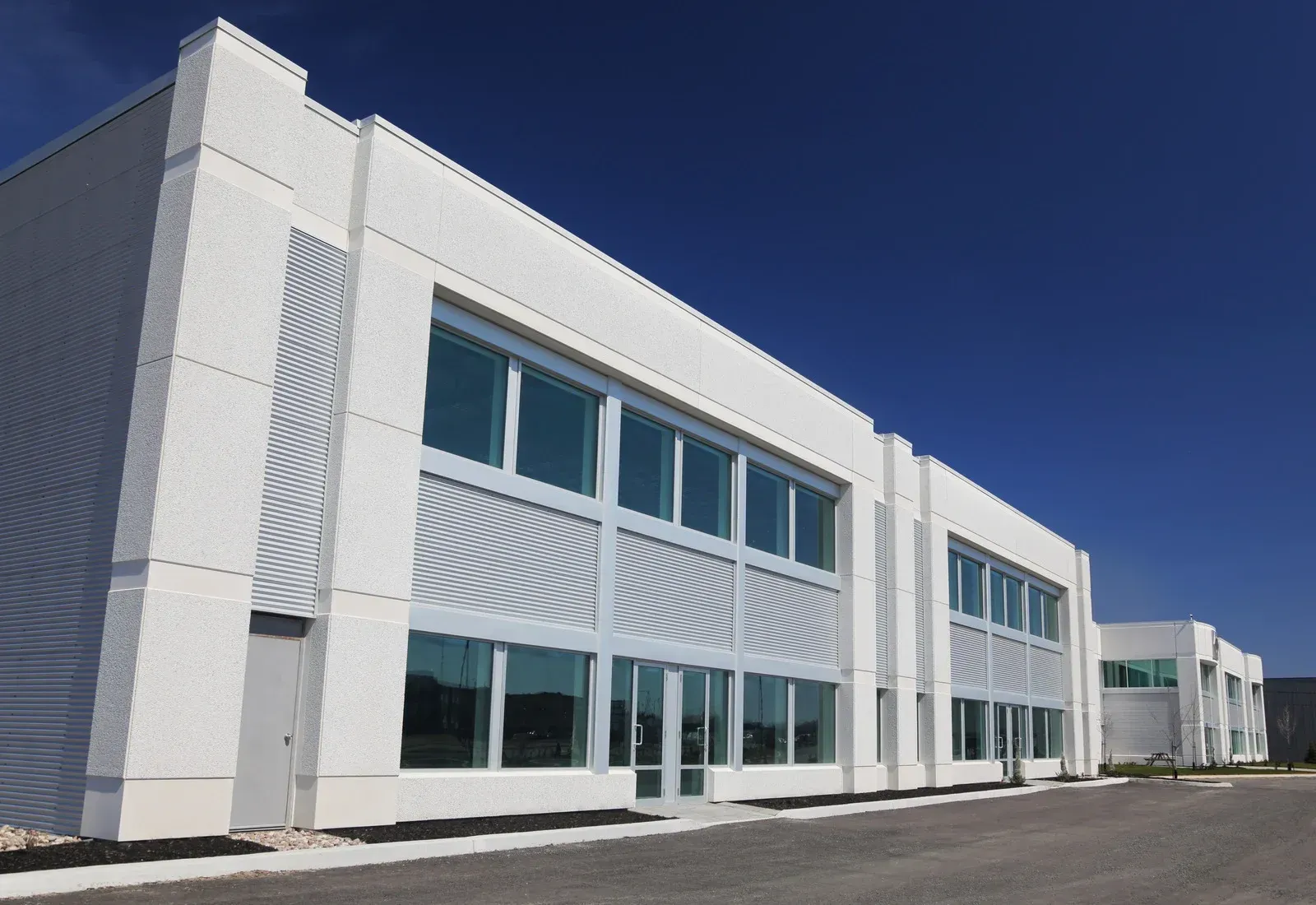 White modern commercial building with large windows against a blue sky.