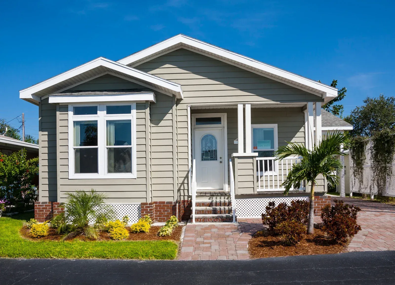 Small, light green house with white trim, porch, and a blue sky.