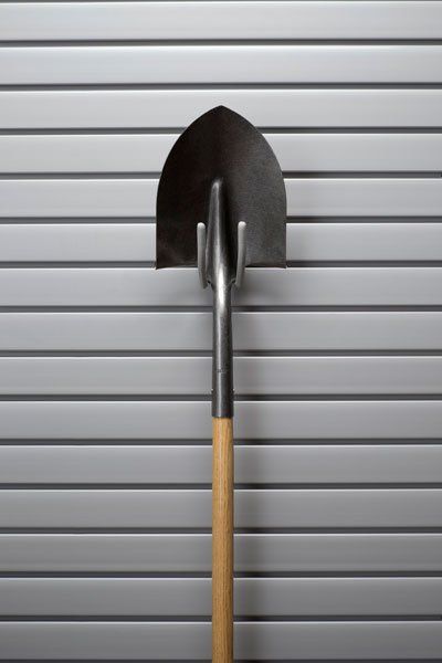 A shovel is hanging on a hook on a wall.