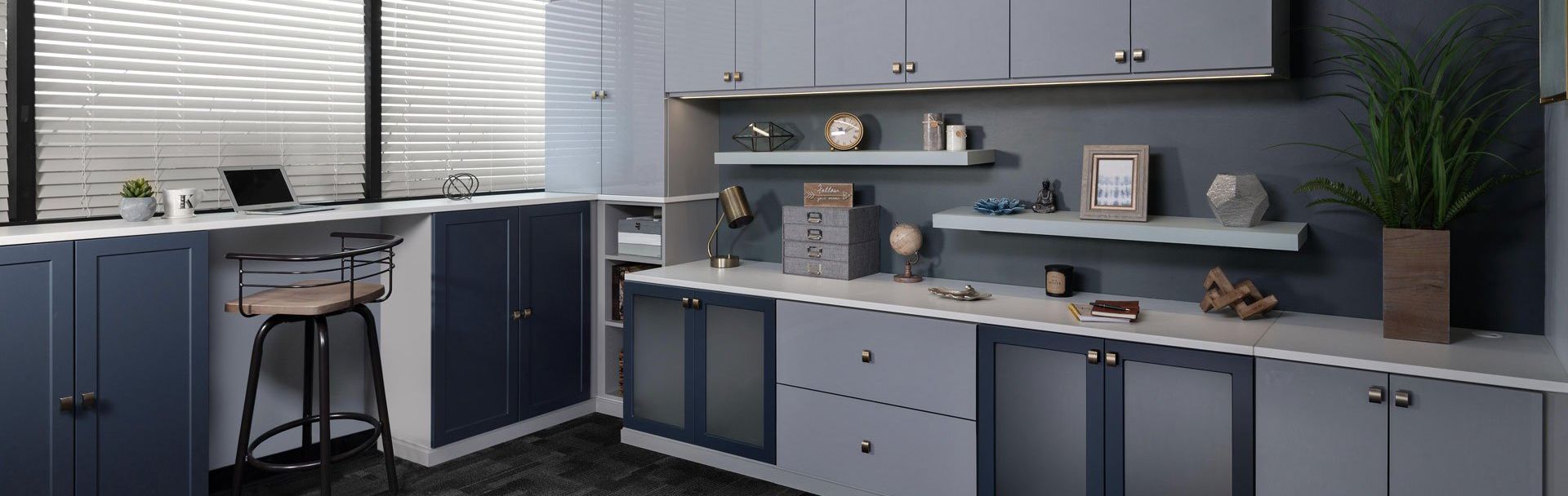 A Home Office with a lot of cabinets and shelves and a desk with a laptop on it.