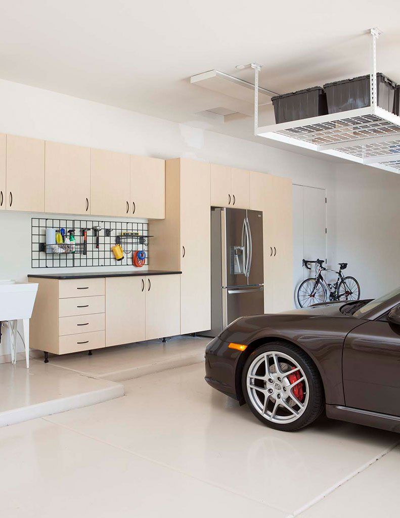 A car is parked in a garage next to a kitchen.