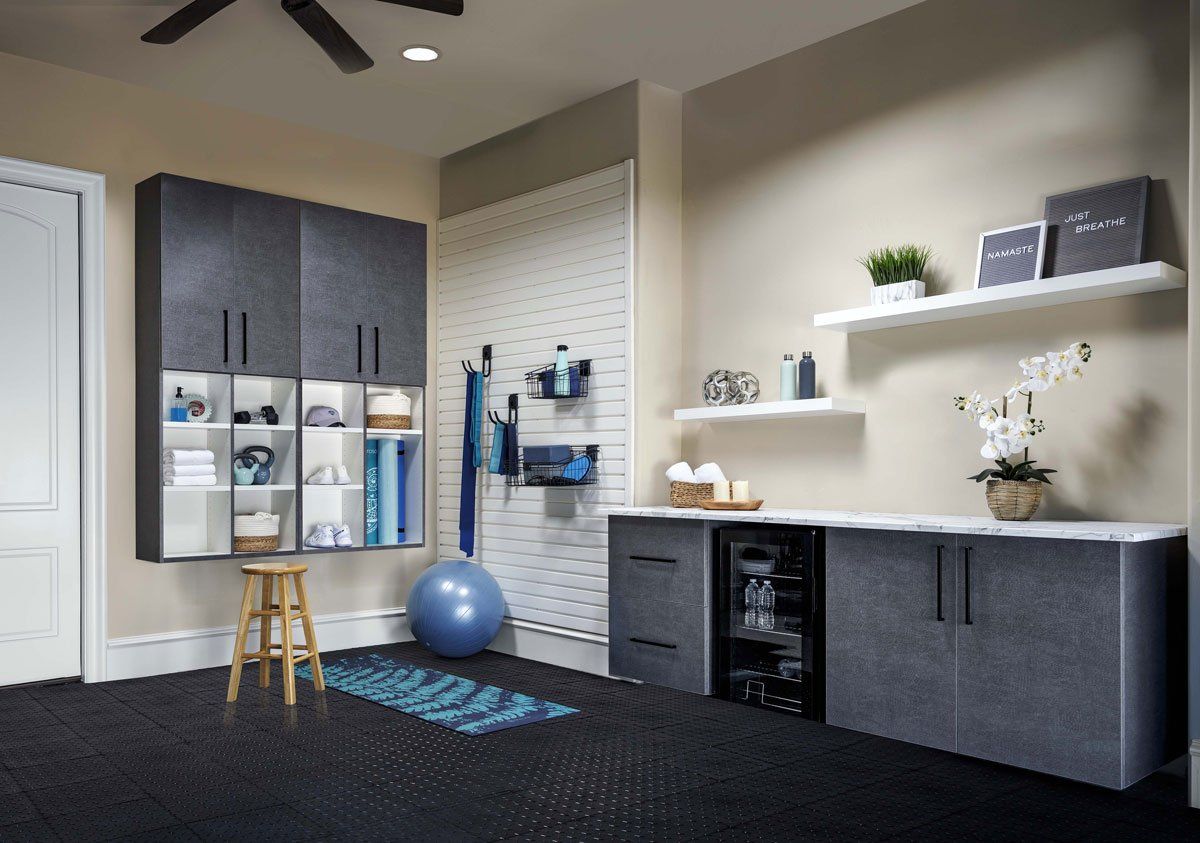 a garage with a ceiling fan , cabinets , shelves , a stool and a yoga mat .