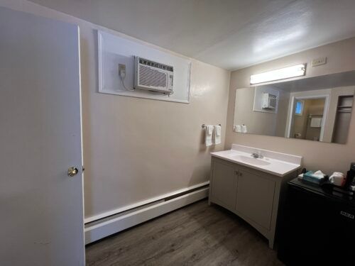 A bathroom with a sink , mirror and air conditioner.