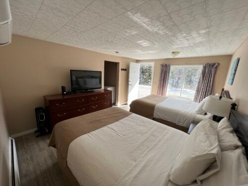 A hotel room with two beds and a flat screen tv.