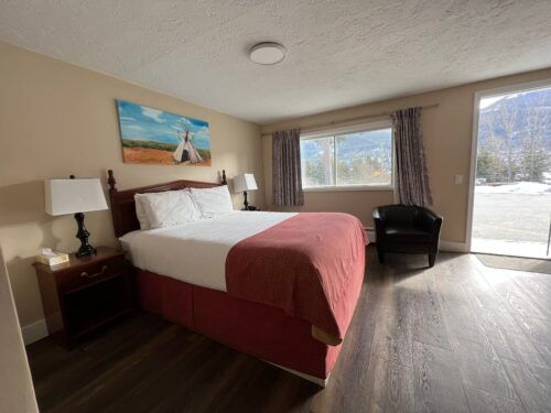 A hotel room with a king size bed and a chair.