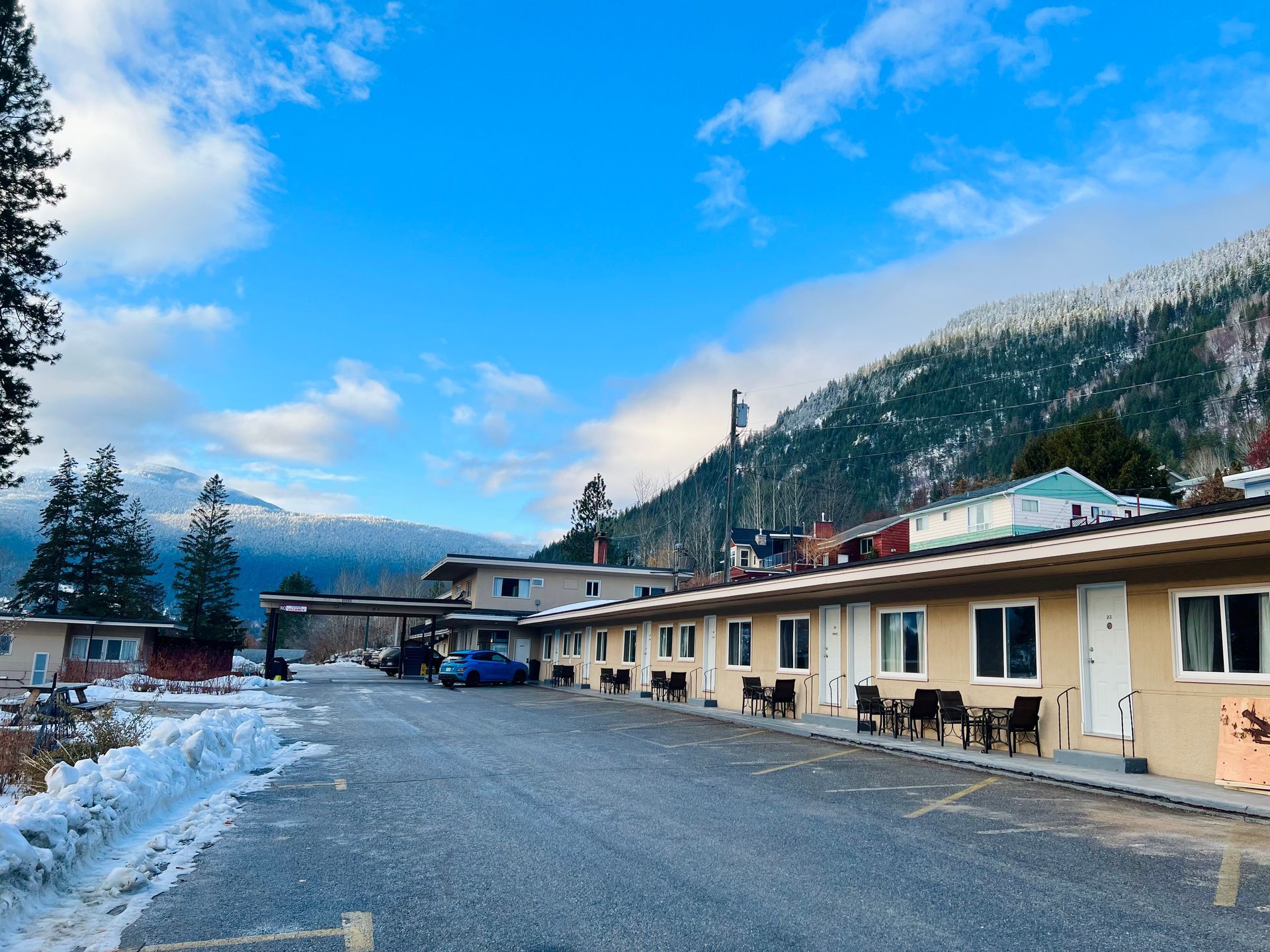 A motel with snow on the ground and mountains in the background.
