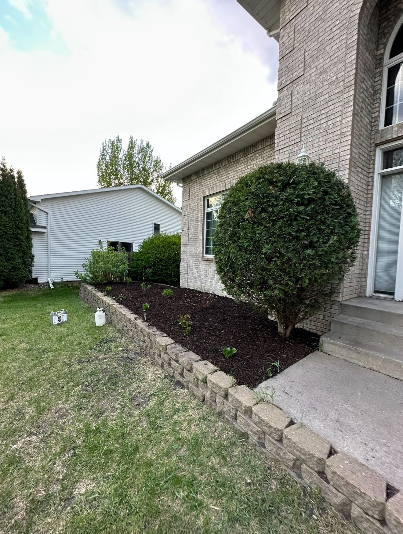 Front yard landscaping with trimmed shrubs, mulch bed, stone edging, and a house exterior