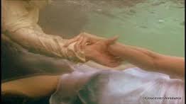 Two hands clasped underwater in a warm, hazy pool scene