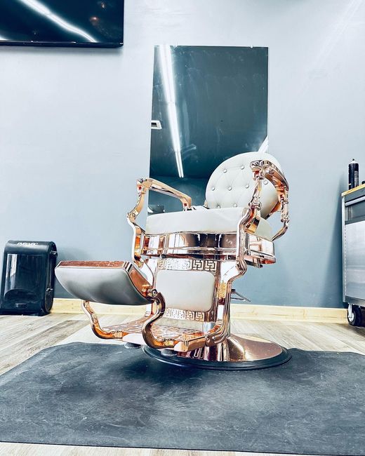 Vintage copper-and-white salon chair on a black mat in a gray room