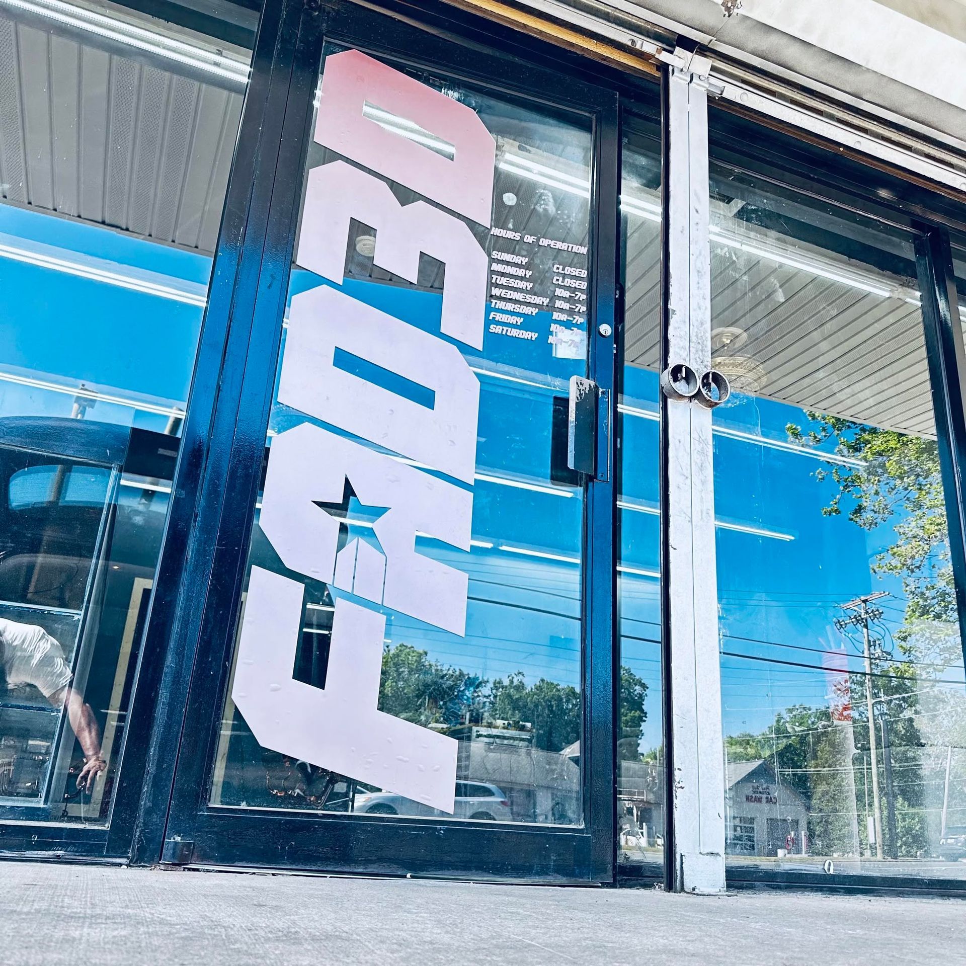FedEx storefront sign on a glass door, with blue and pink branding reflected in the window.