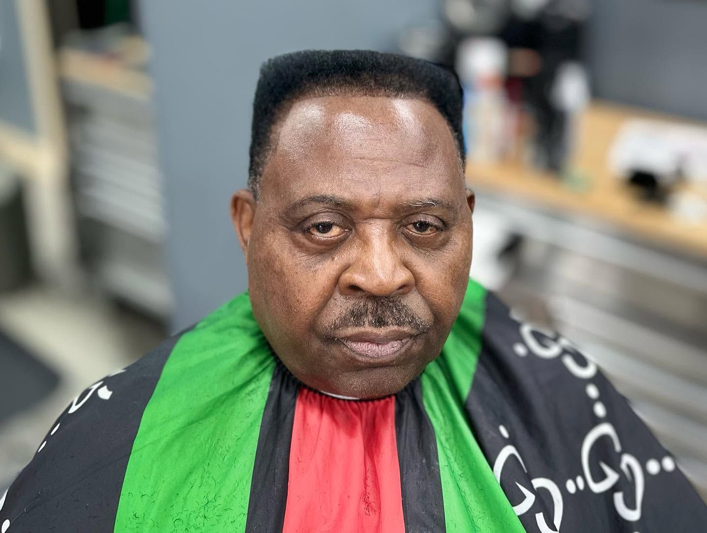 Portrait of a person in a green and red garment, looking at the camera indoors.