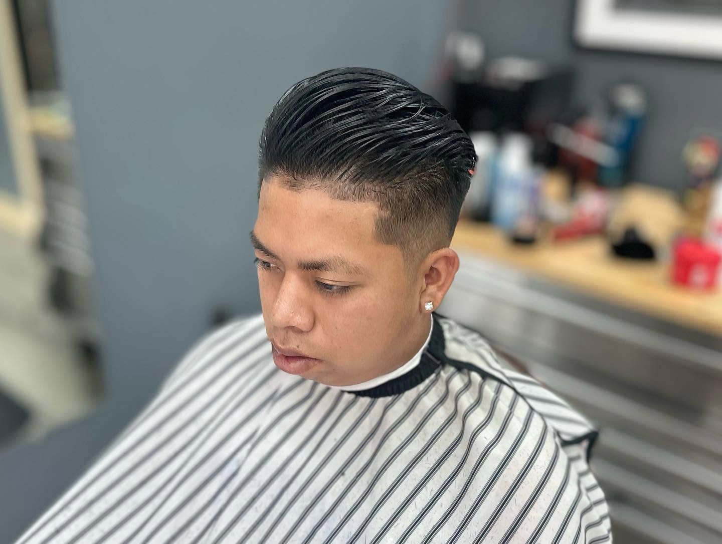 Person with a striped barber cape getting a haircut in a salon
