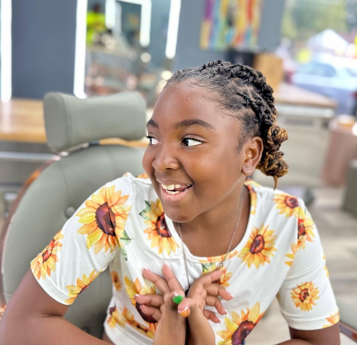 Smiling child in sunflower shirt leaning on a table in a bright indoor space