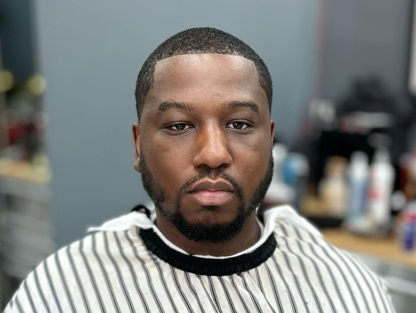 Close-up portrait of a man in a striped sweater, looking at the camera indoors.
