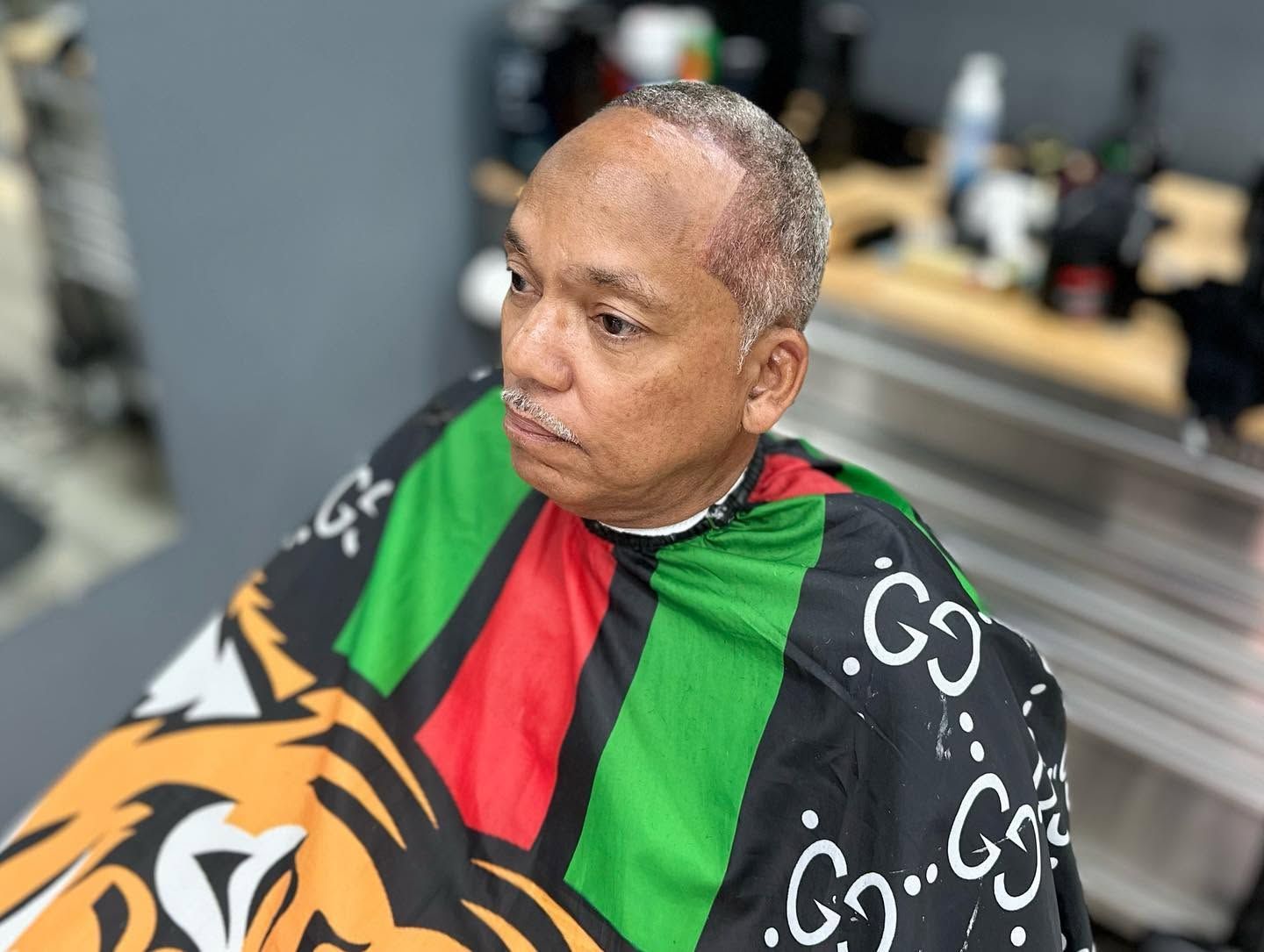 Man in green and red jersey holding a tiger banner, seated indoors with blurred background