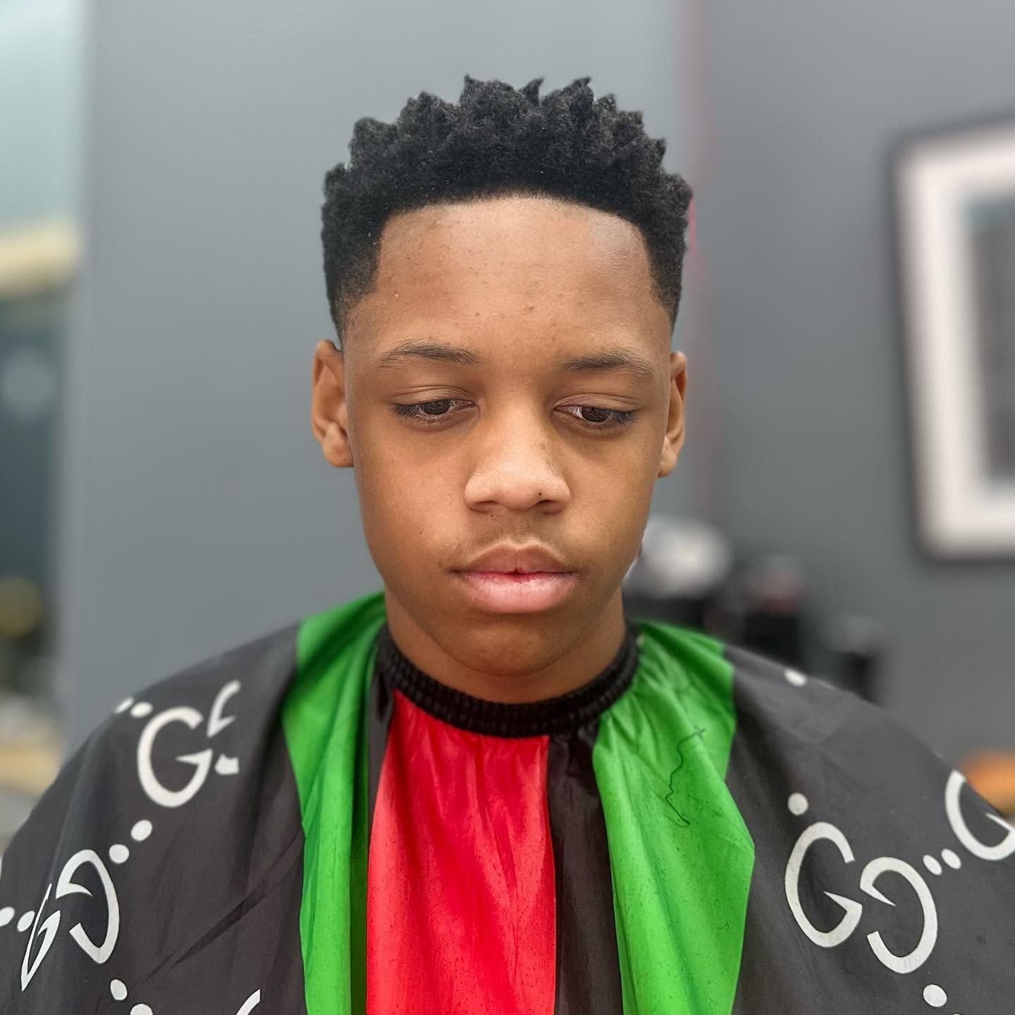 Portrait of a person wearing a black, green, and red patterned shirt against a gray background