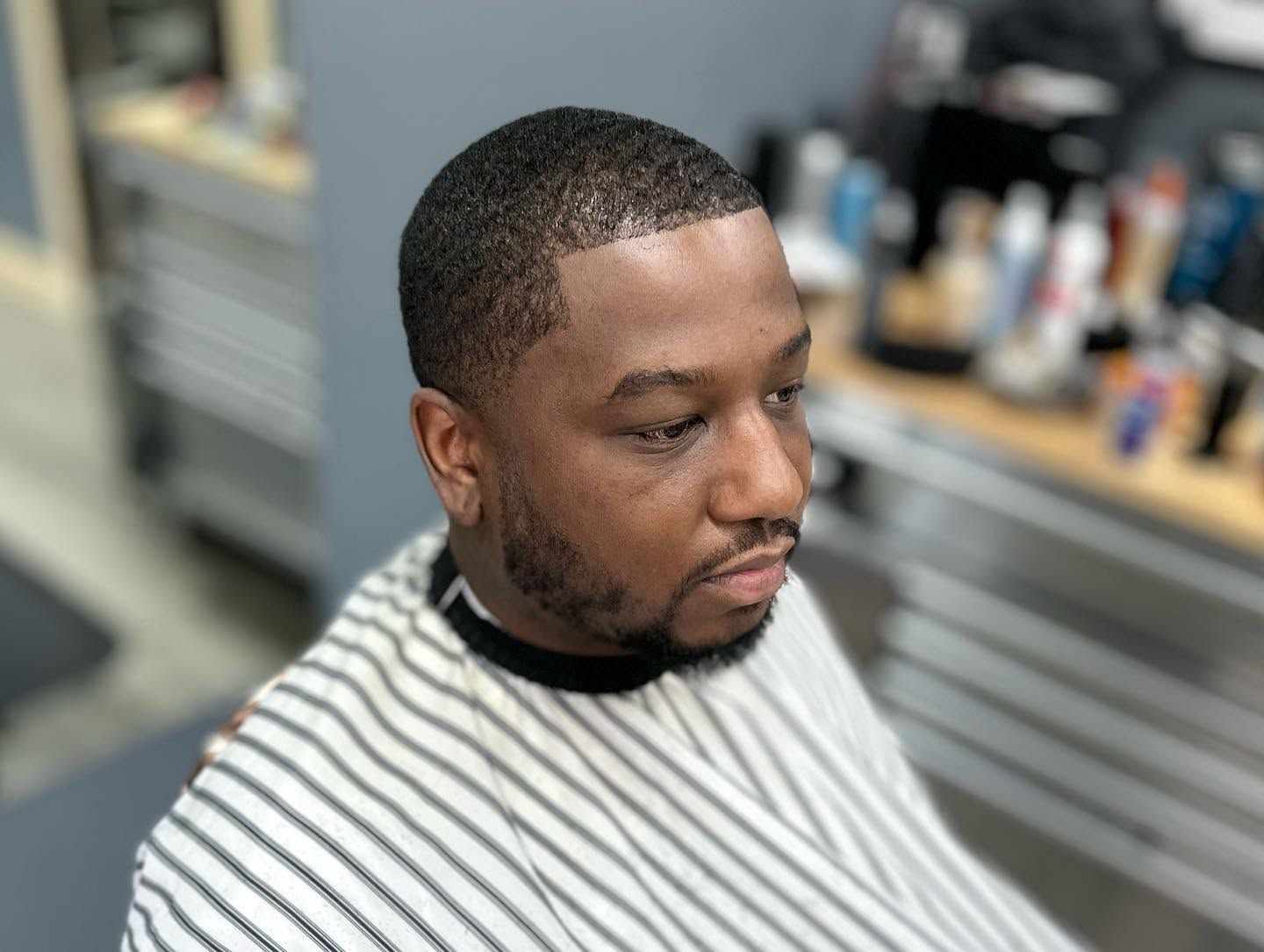 Man in striped barber cape getting a haircut in a barbershop