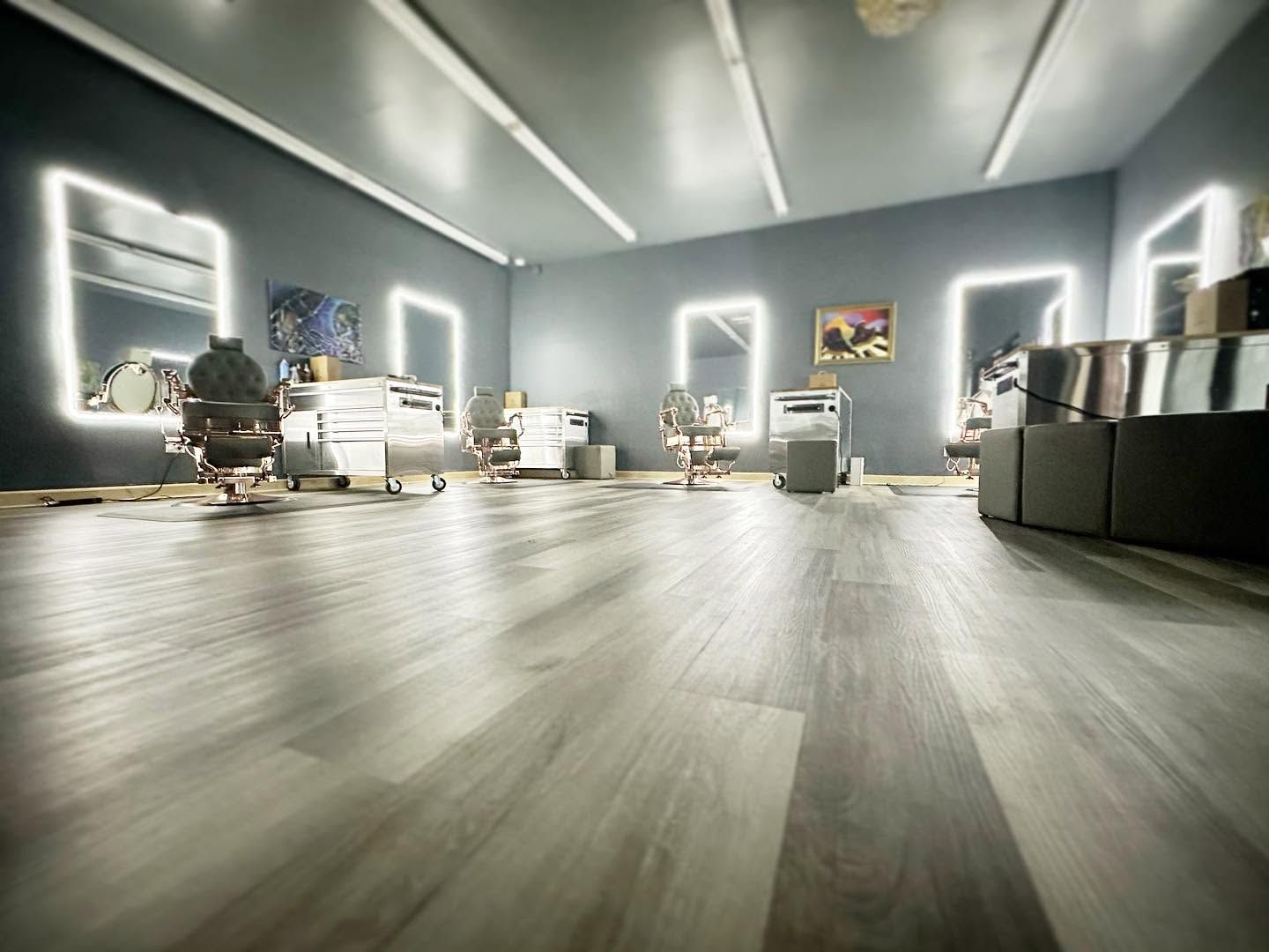 Modern living room with gray walls, wood flooring, white furniture, and bright windows.