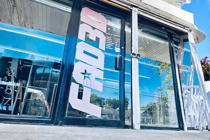 Storefront with large vertical “FIVE” signage and glass windows under a bright blue sky