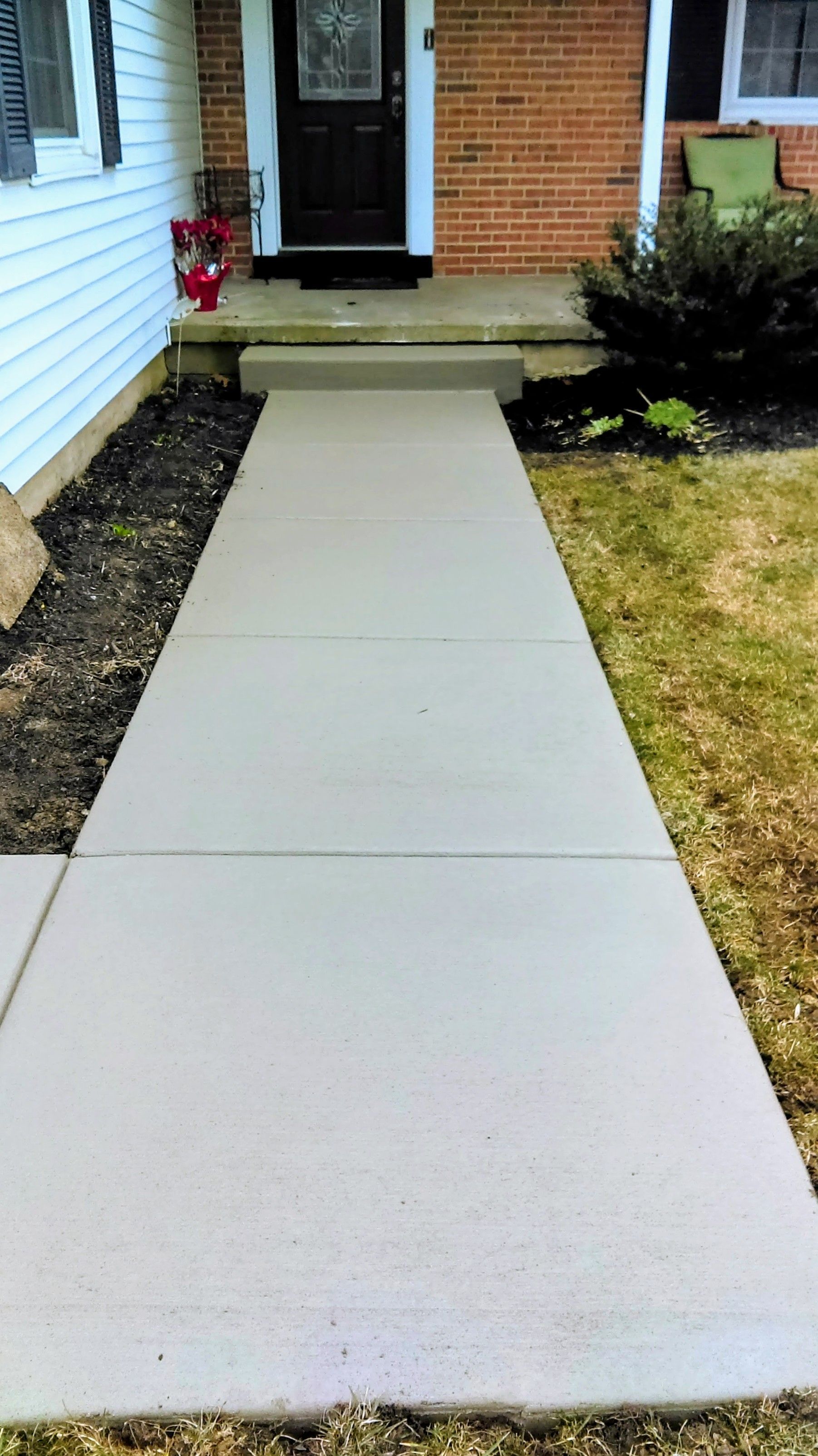 Concrete walkway leading to a front door of a house with steps.