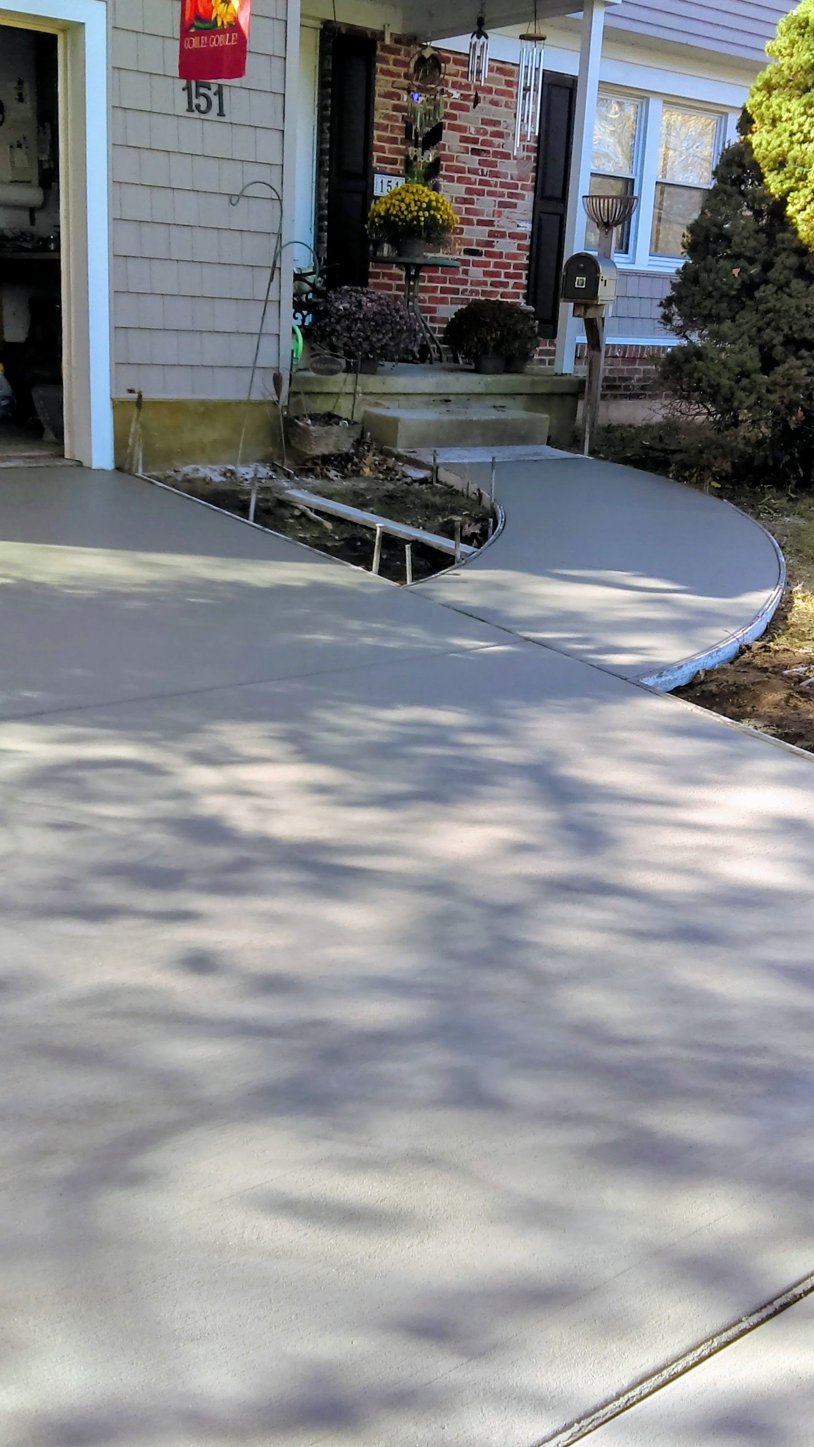 New concrete driveway and sidewalk leading to a house entrance.
