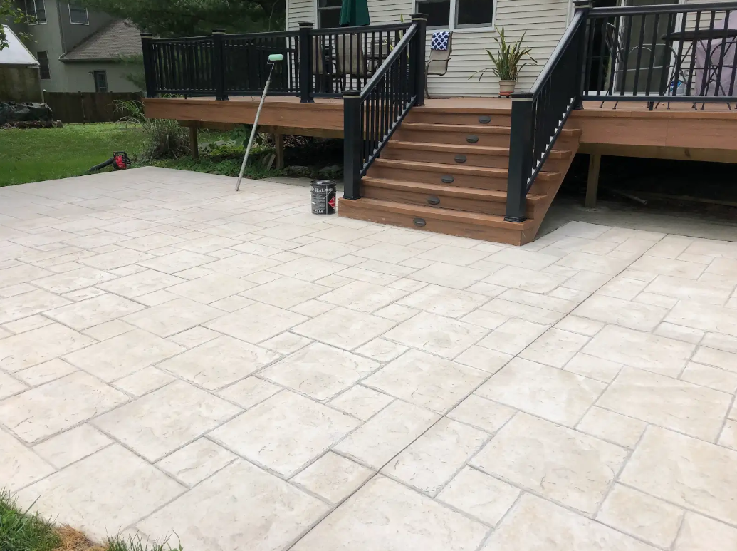 A patio with a deck and stairs in front of a house.