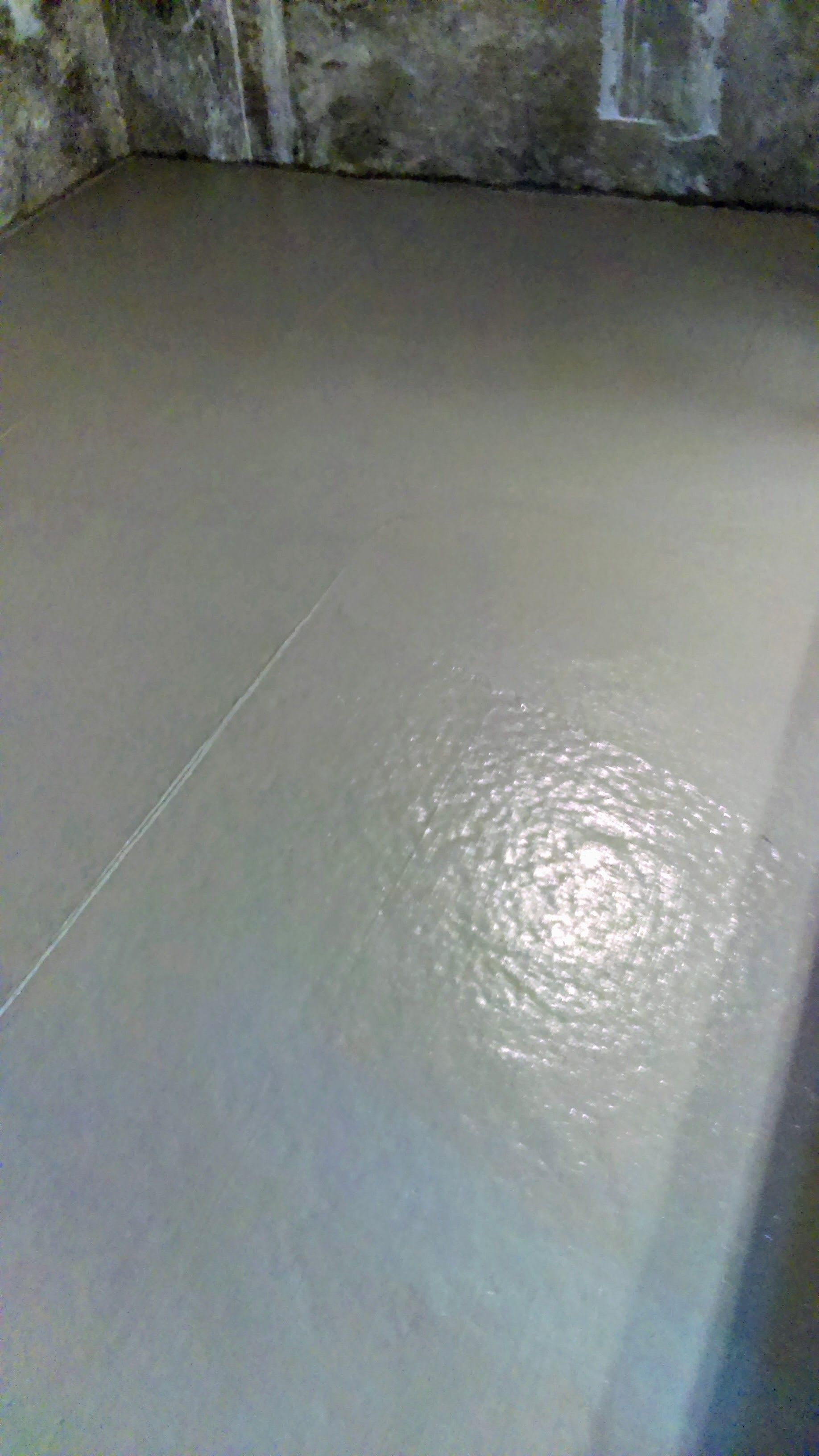 Newly poured, smooth, gray concrete floor in a room.