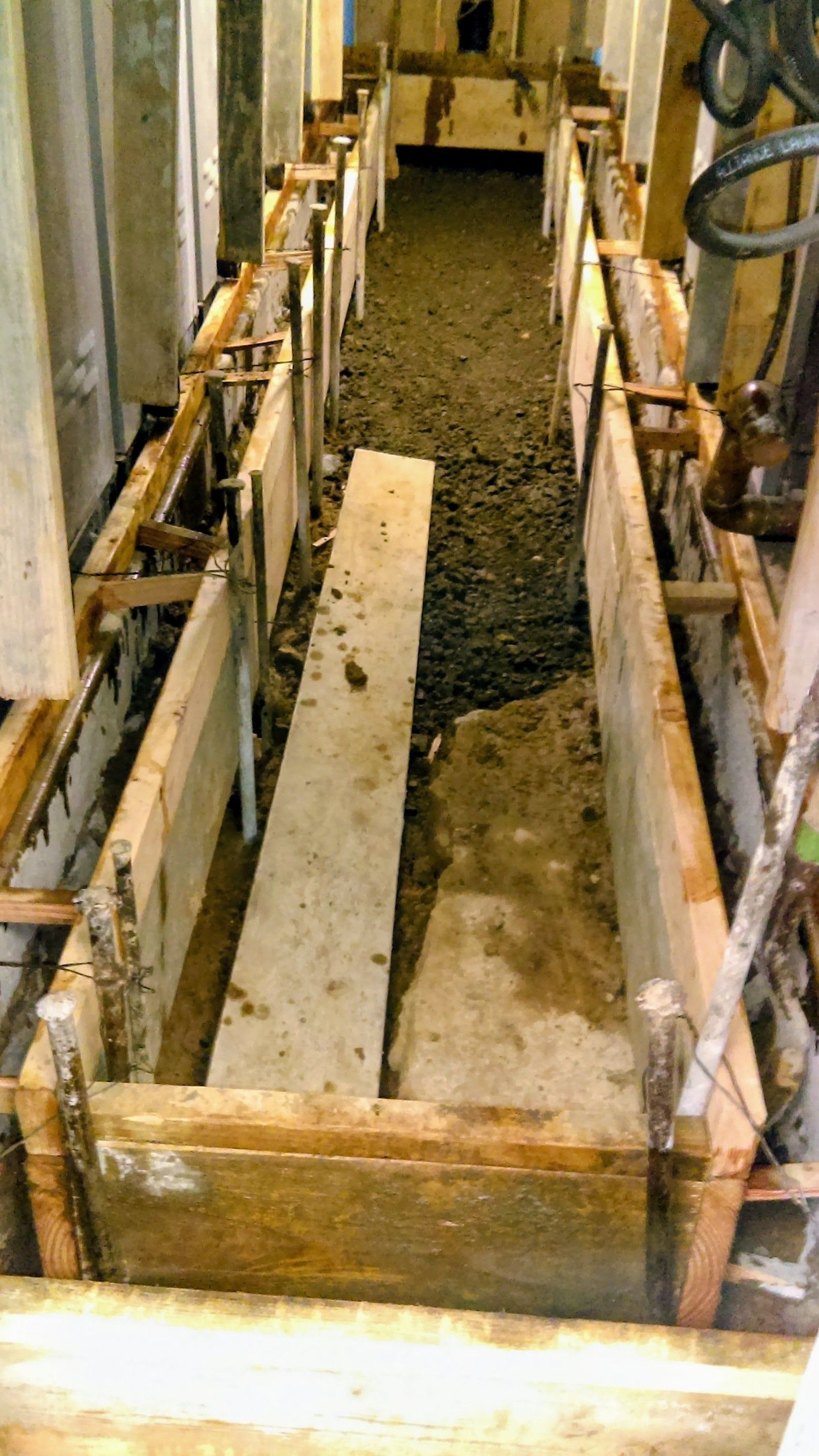 Concrete being poured into wooden forms in a construction site.