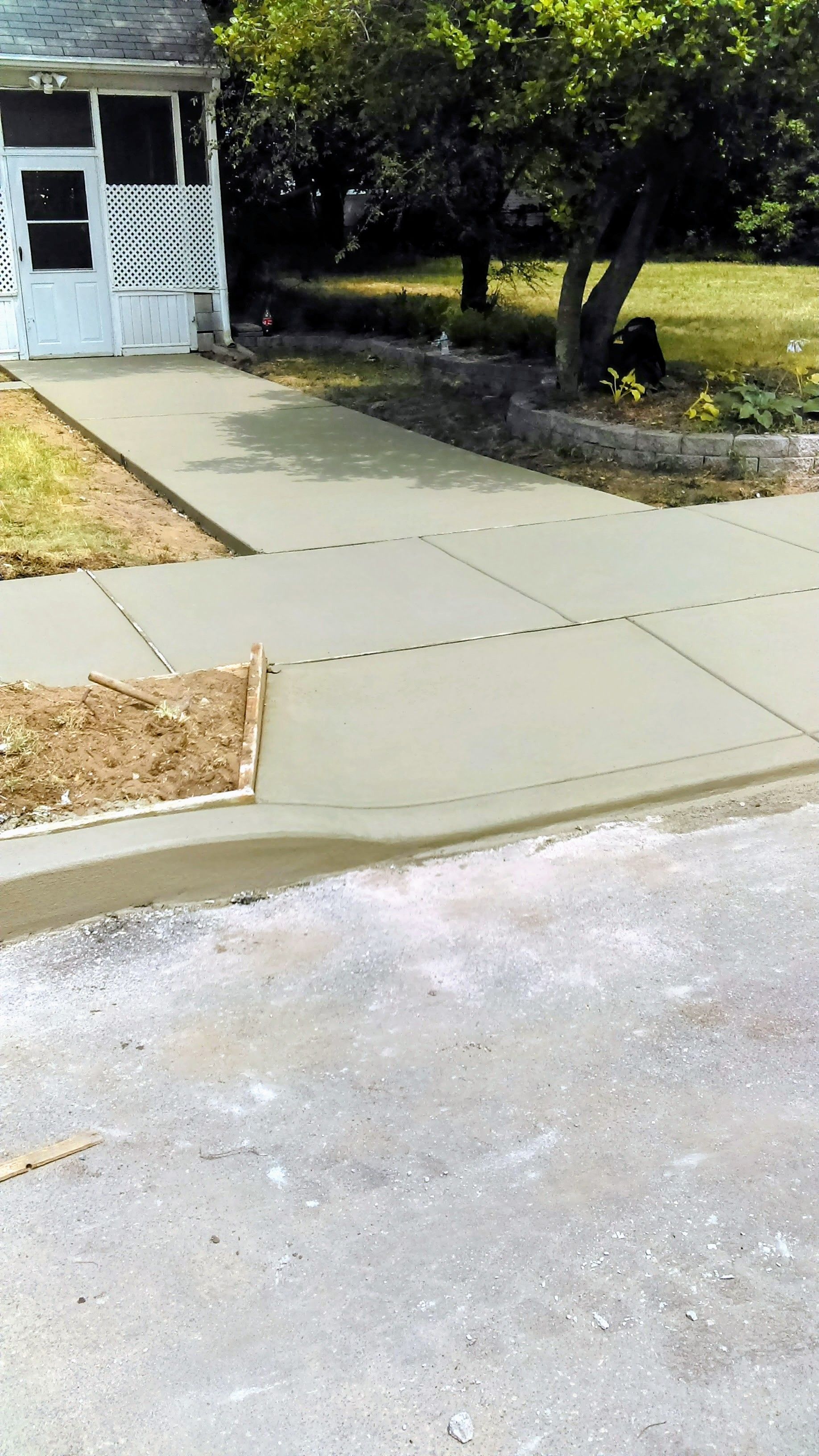 Freshly poured concrete driveway and sidewalk in front of a house.