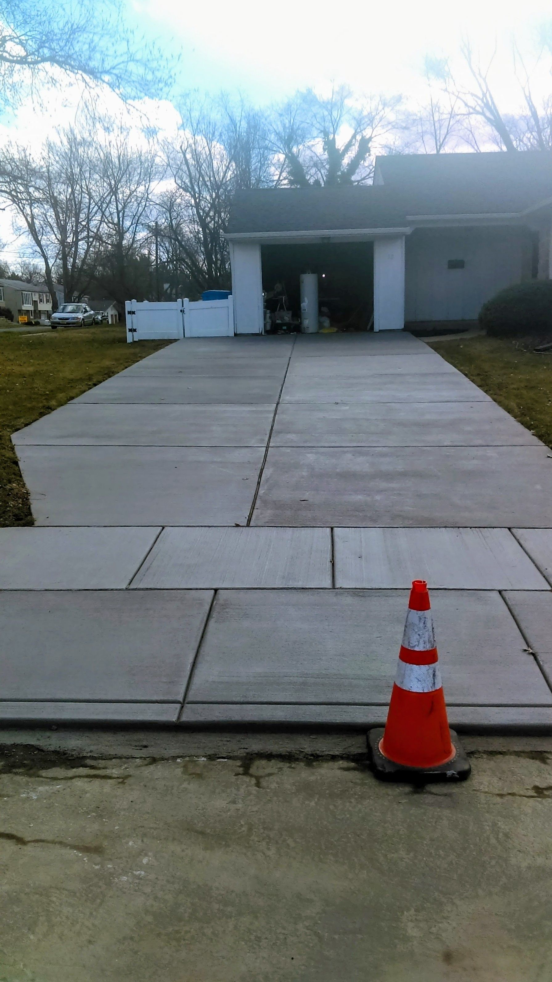 Orange traffic cone on a gray concrete driveway, leading to a garage entrance.