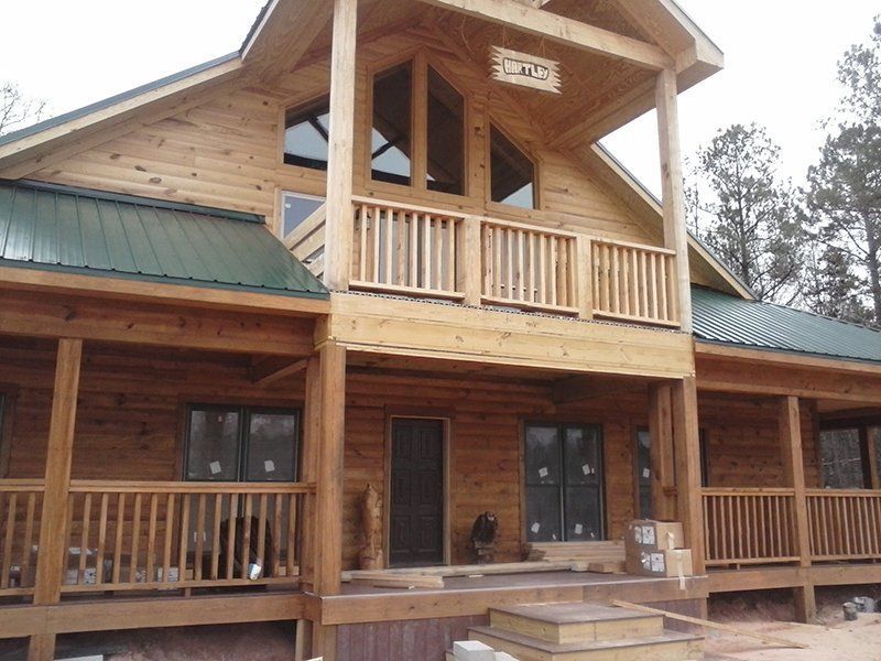 A large wooden house with a green roof and a balcony