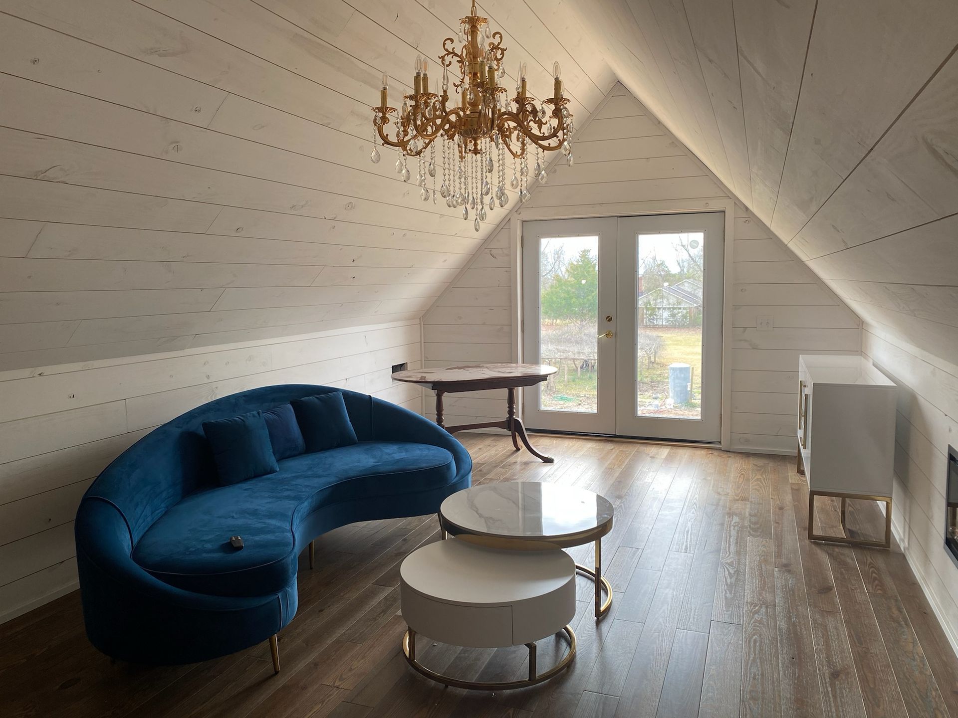 A living room with a blue couch and a chandelier