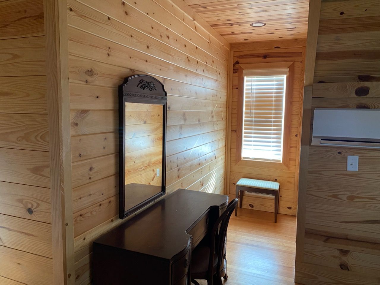 A wooden room with a desk and a mirror