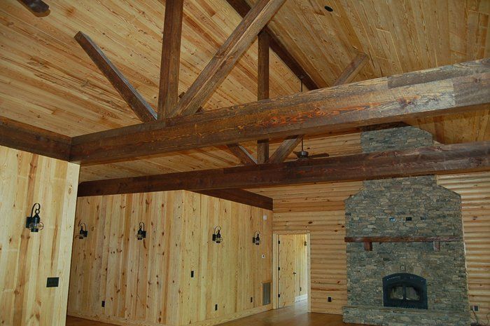 A living room with wood paneling and a stone fireplace