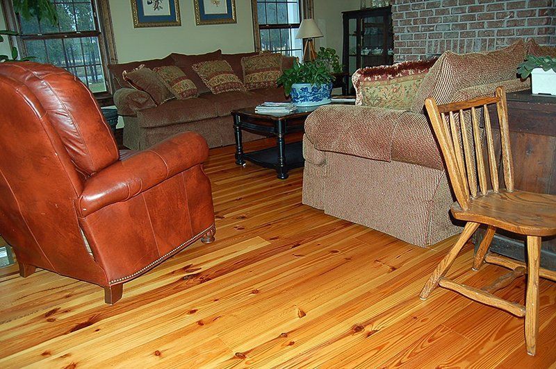 A living room with wooden floors , a couch , chairs , and a fireplace.