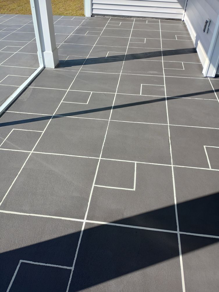 A gray concrete patio surface with a painted, geometric white grid pattern of varying square sizes.