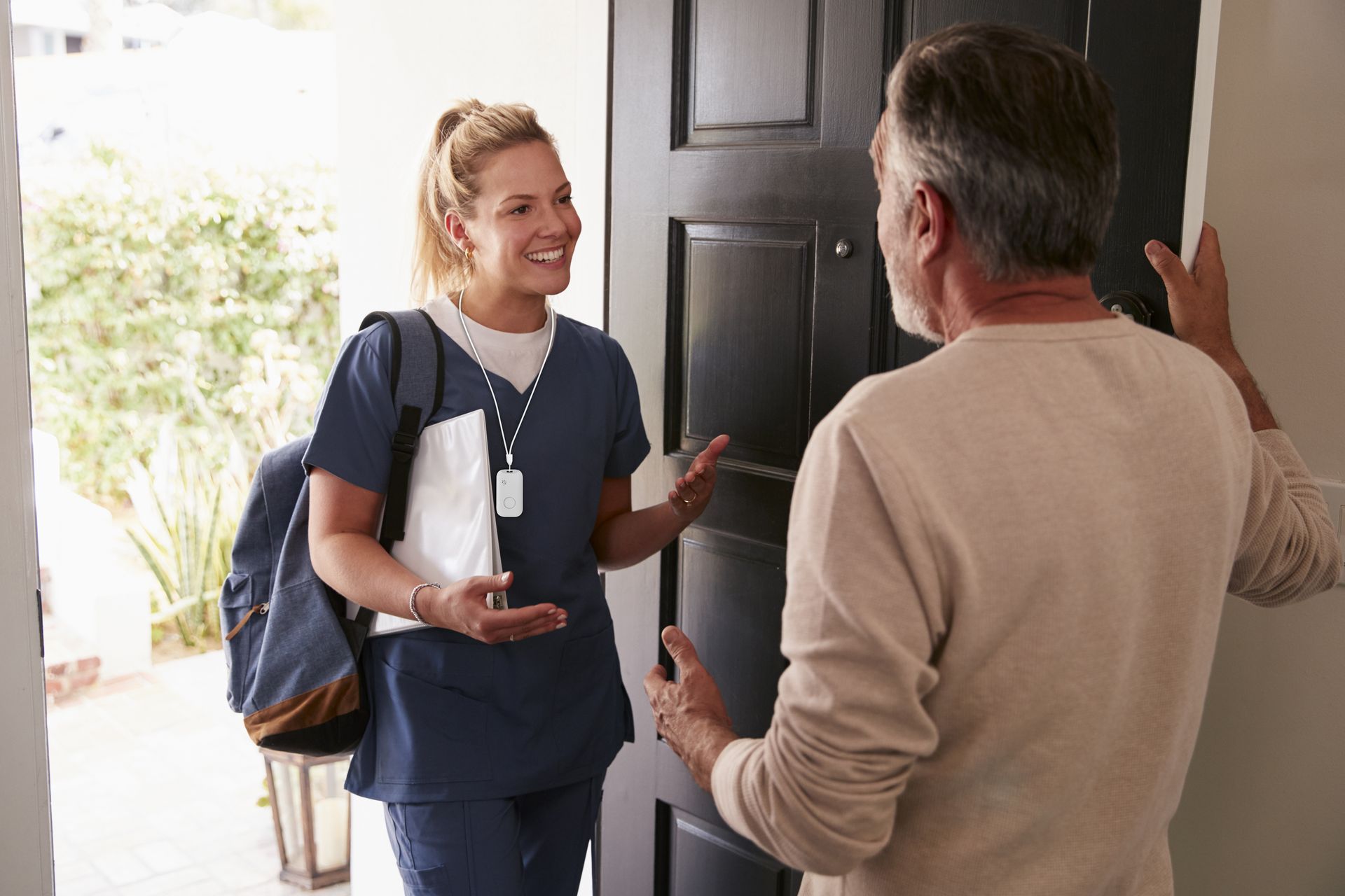 Lady in doorway providing in-home community care wearing an INS LifeGuard Smarttracker, personal alarm for Lone Workers