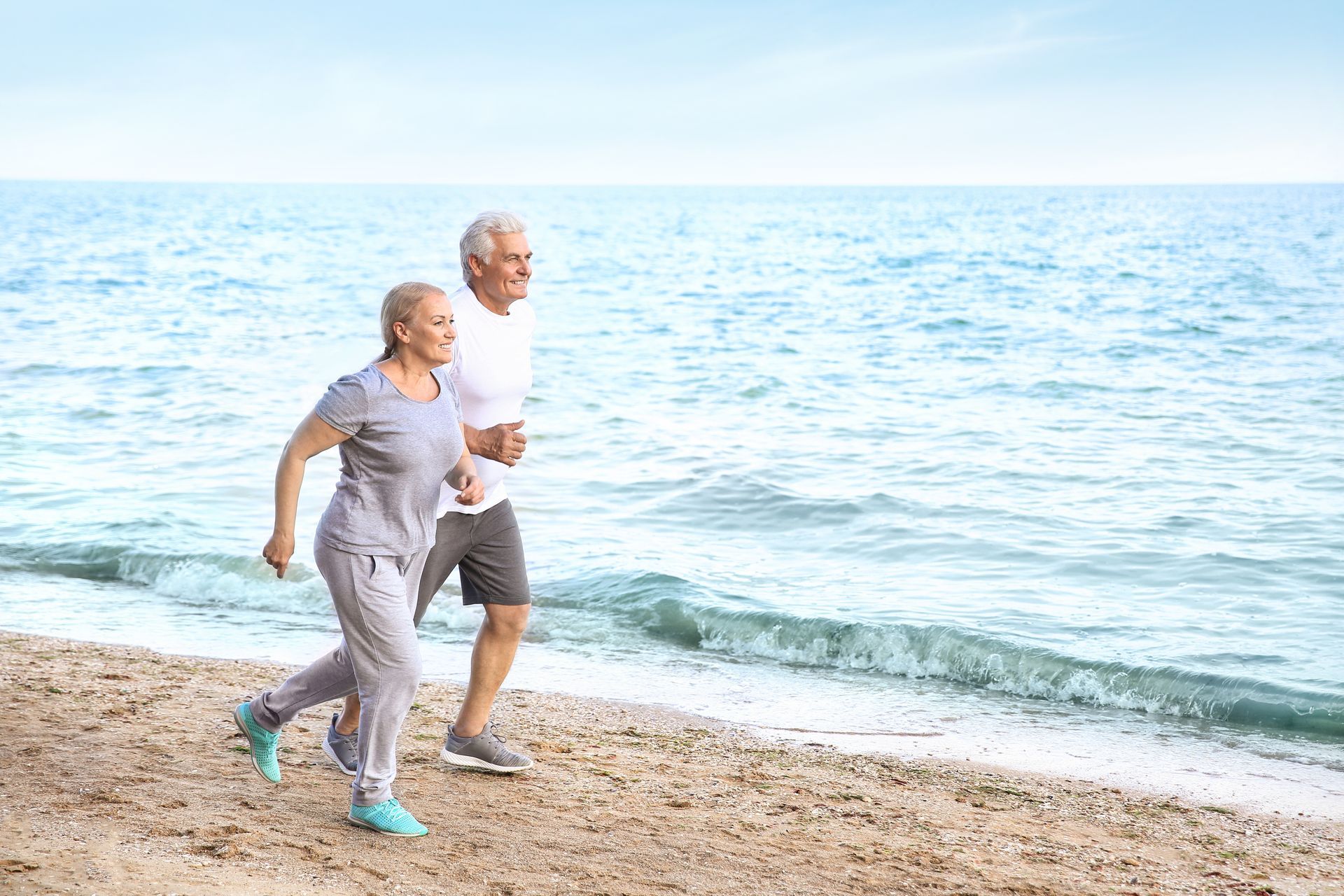 two seniors running on the beach