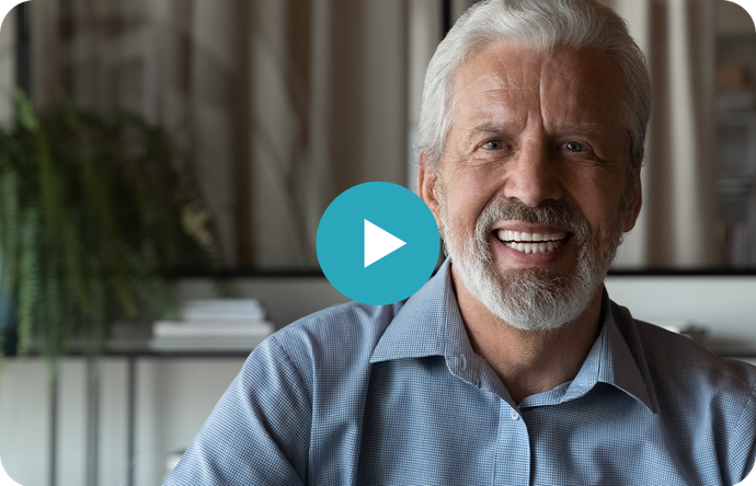 An older man with a beard is smiling and looking at the camera.