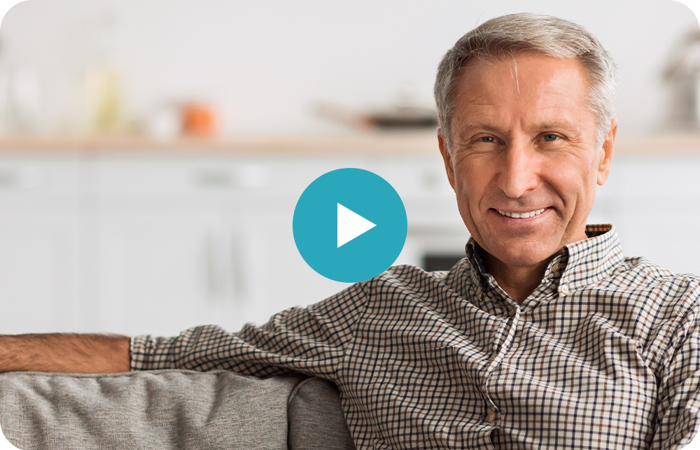 A man is sitting on a couch with his arms crossed and smiling.