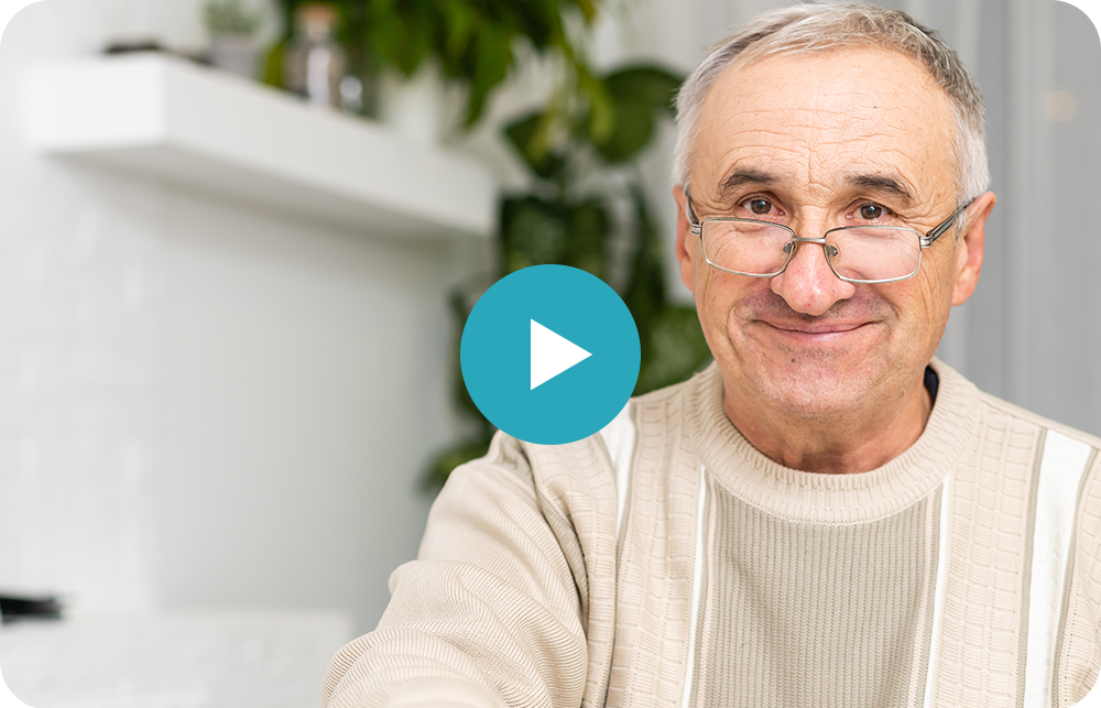 An older man wearing glasses is smiling and looking at the camera.