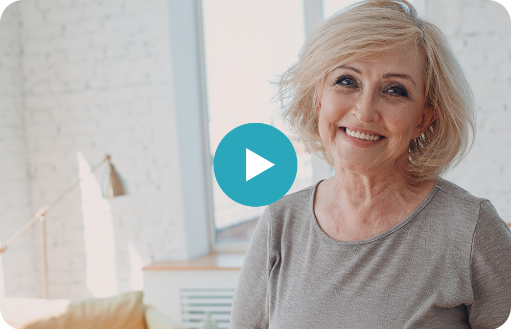 An older woman is smiling for the camera in a living room.
