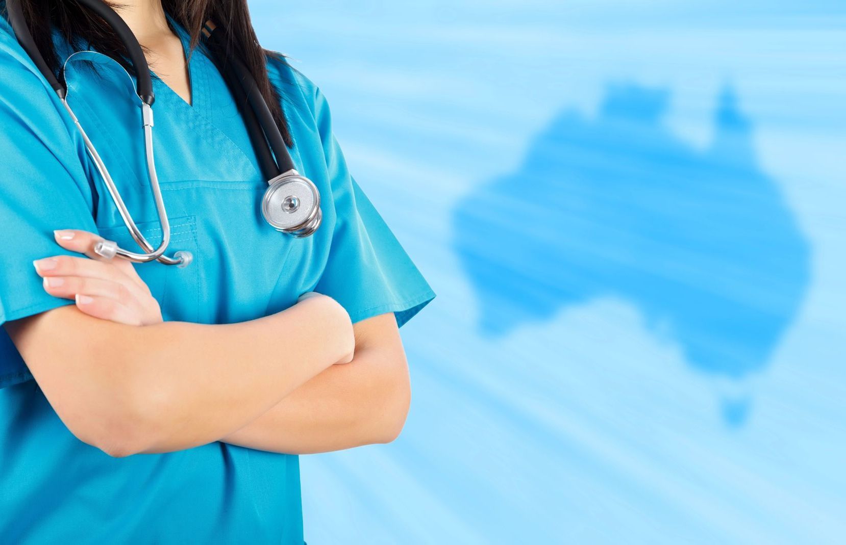 A nurse with a stethoscope around her neck is standing with her arms crossed in front of a map of australia.