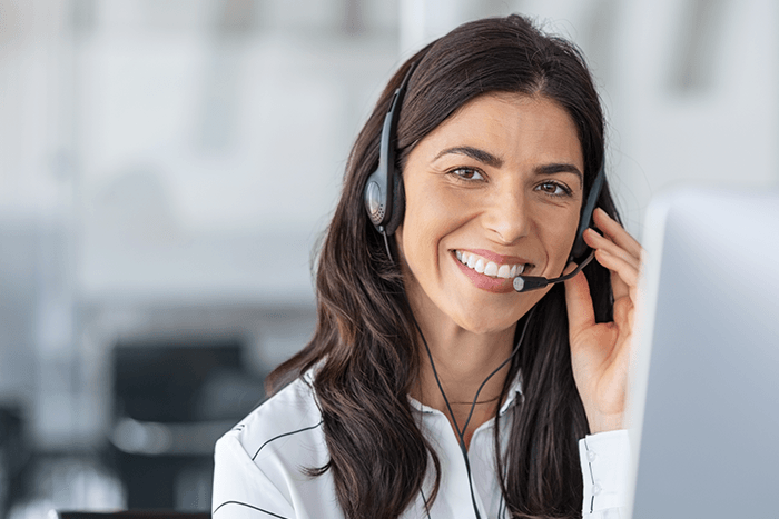 Smiling customer support agent wearing a headset at a desk, speaking on the phone representing call centre solutions