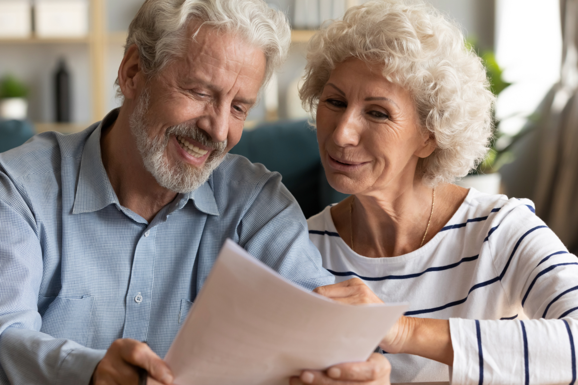 Older couple smiling as they read through a letter together at home