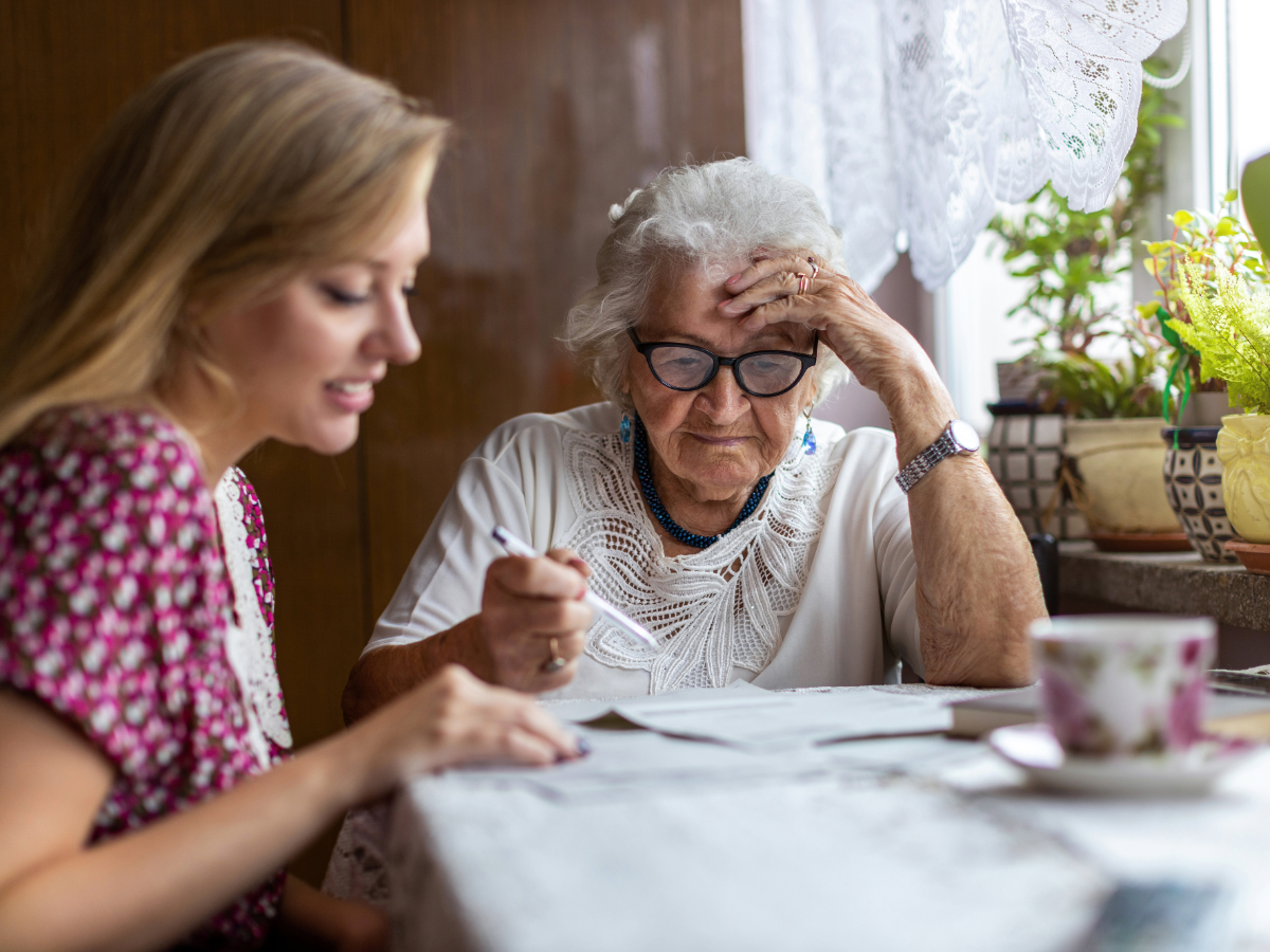 Older woman discussing her changing care needs with a younger woman at home.