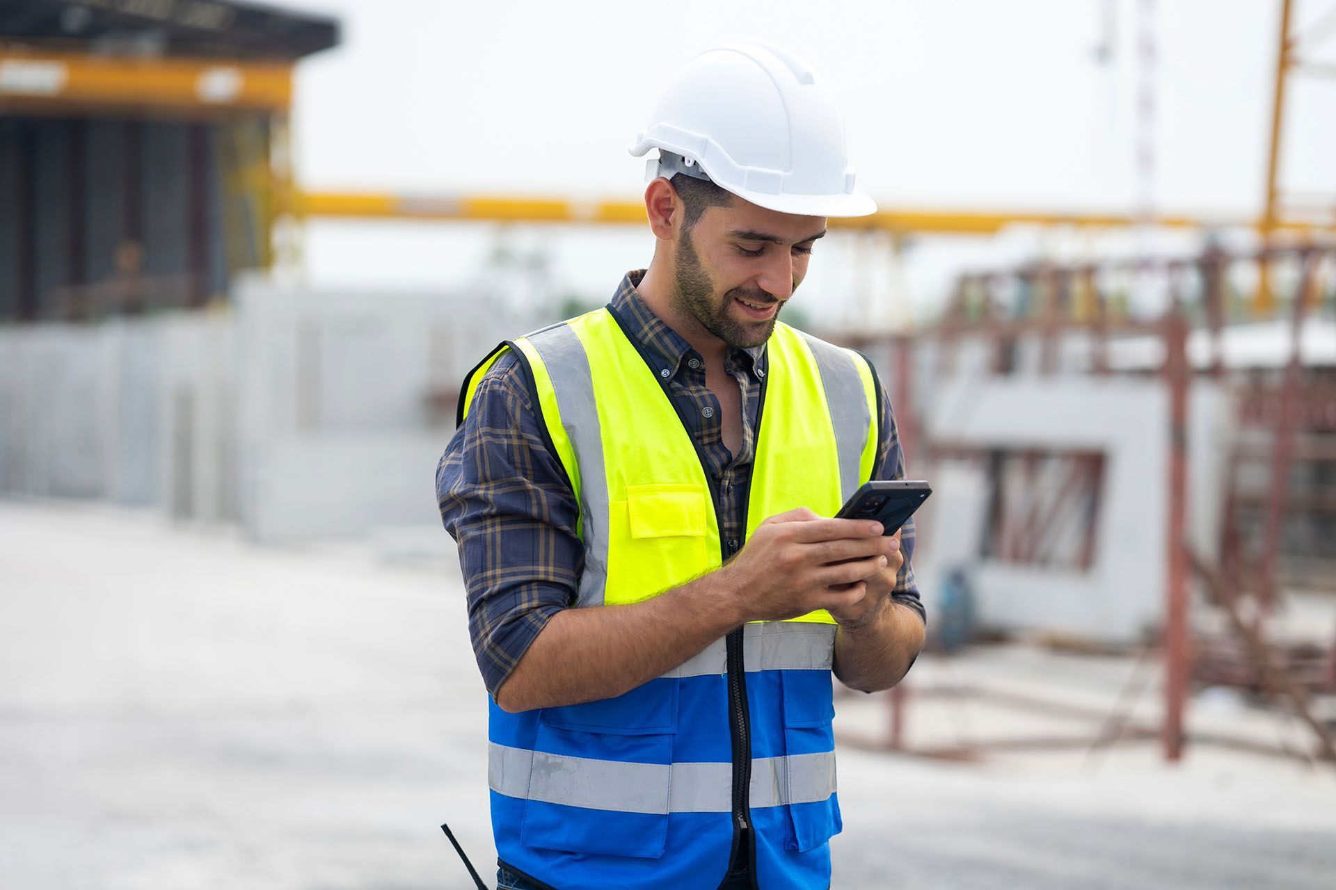 A construction worker is using a cell phone on a construction site.